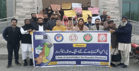 Participants standing outside holding peaceful elections banner